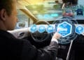 Driver activating "Autonomous Mode" on a futuristic vehicle dashboard.